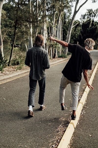 Two young guys walking along a road talking 