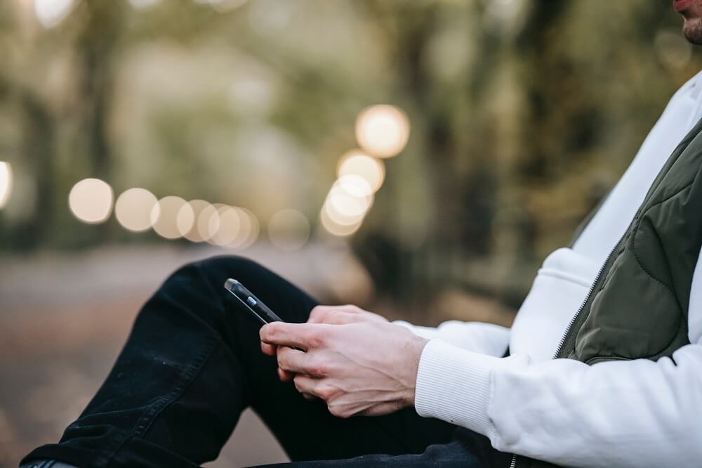 Isolated man sitting on his own texting on his phone 