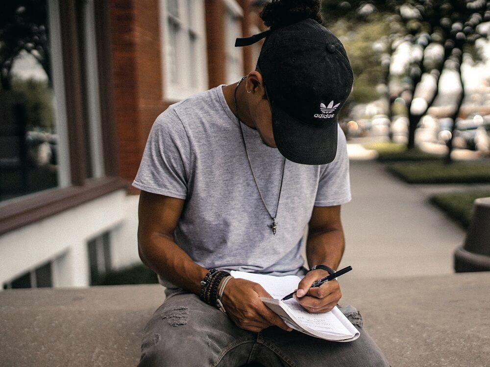 A man sitting outside journaling his thoughts.