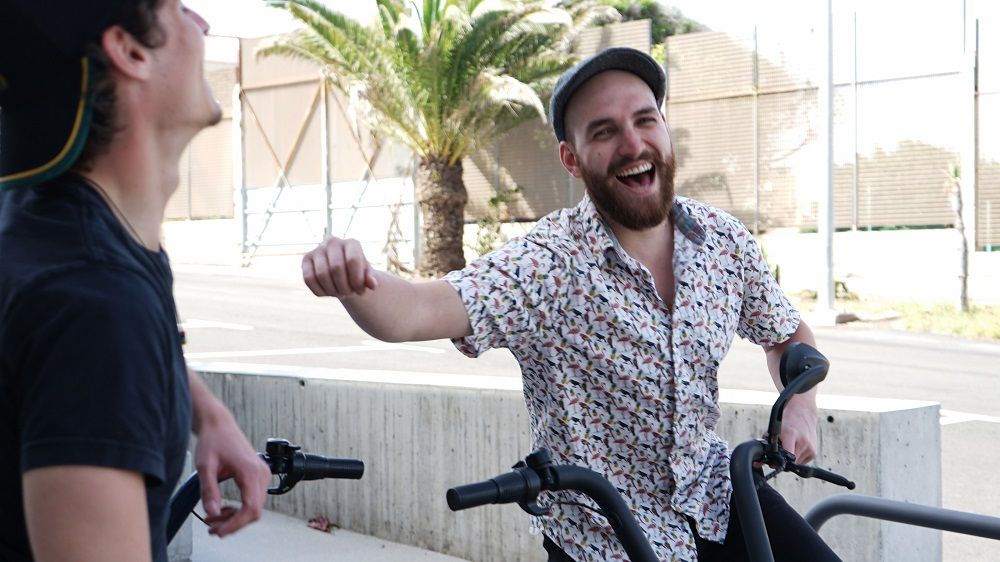 Two men on bikes laughing with one trying to boost the others self-esteem after a job loss