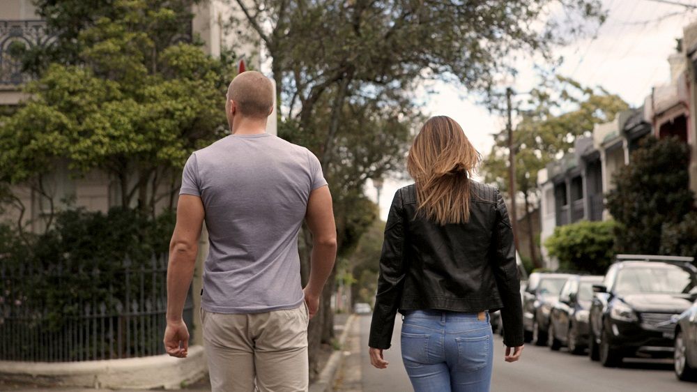 Woman walking in a street with a man who's withdrawing